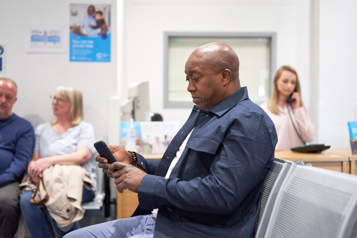 Man in a waiting room looking at his phone.